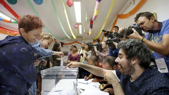 Un ni&ntilde;o, en brazos de su madre, deposita el voto en la urna