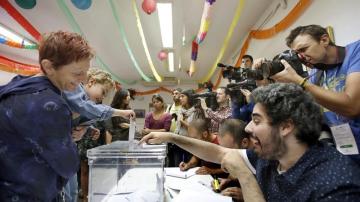 Un niño, en brazos de su madre, deposita el voto en la urna