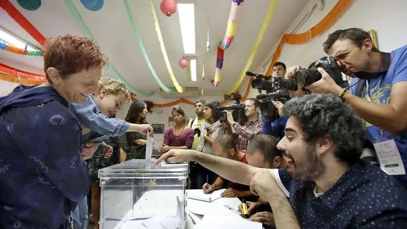 Un niño, en brazos de su madre, deposita el voto en la urna