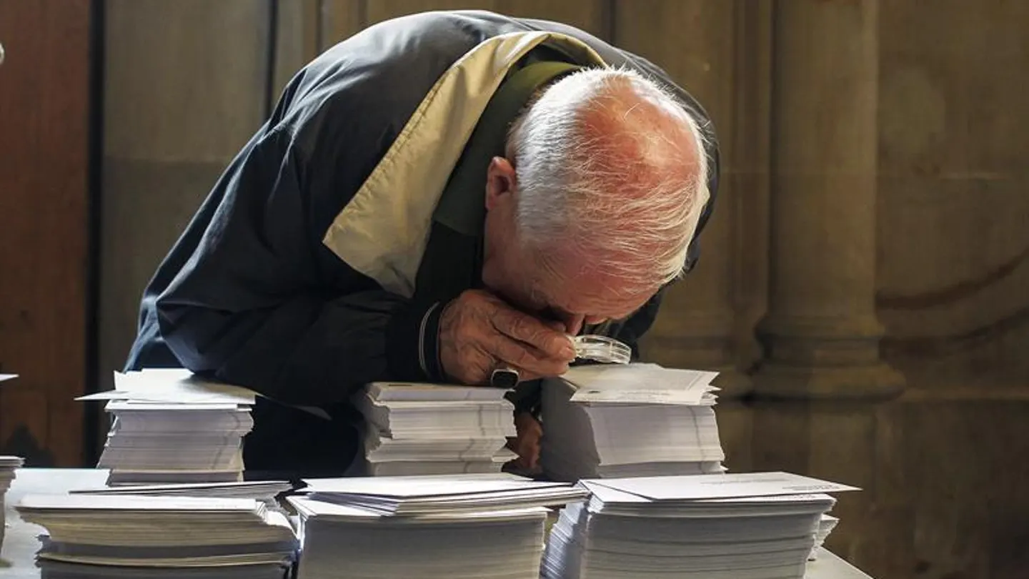 Una persoma observa con una lupa las papeletas de los diferentes partidos del 27S Una persoma observa con una lupa las papeletas de los diferentes partidos del 27S
