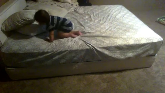 Un bebé a punto de descender de una cama Un bebé a punto de descender de una cama