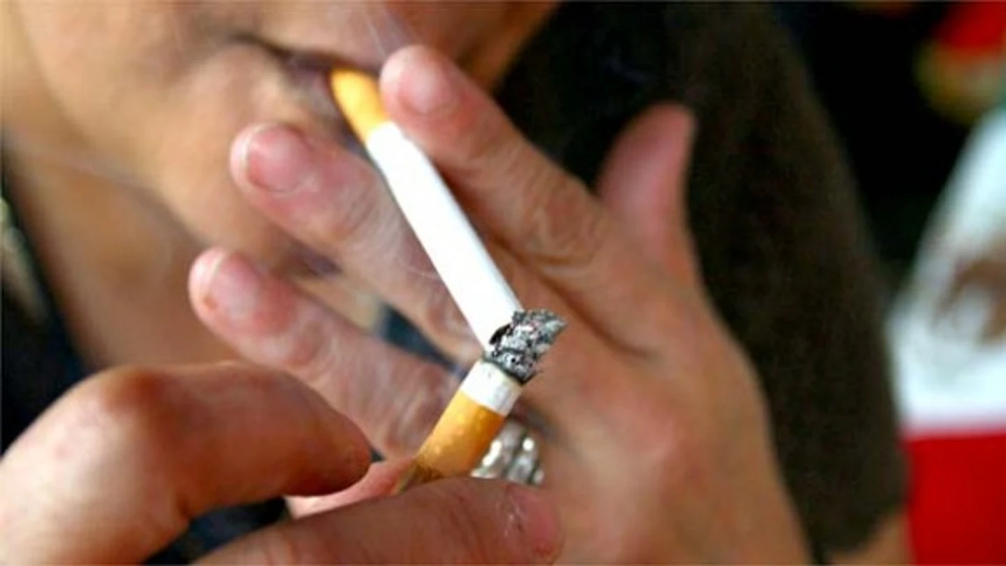 Una persona encendiéndose un cigarro Una persona encendiéndose un cigarro