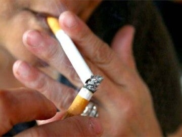 Una persona encendiéndose un cigarro Una persona encendiéndose un cigarro