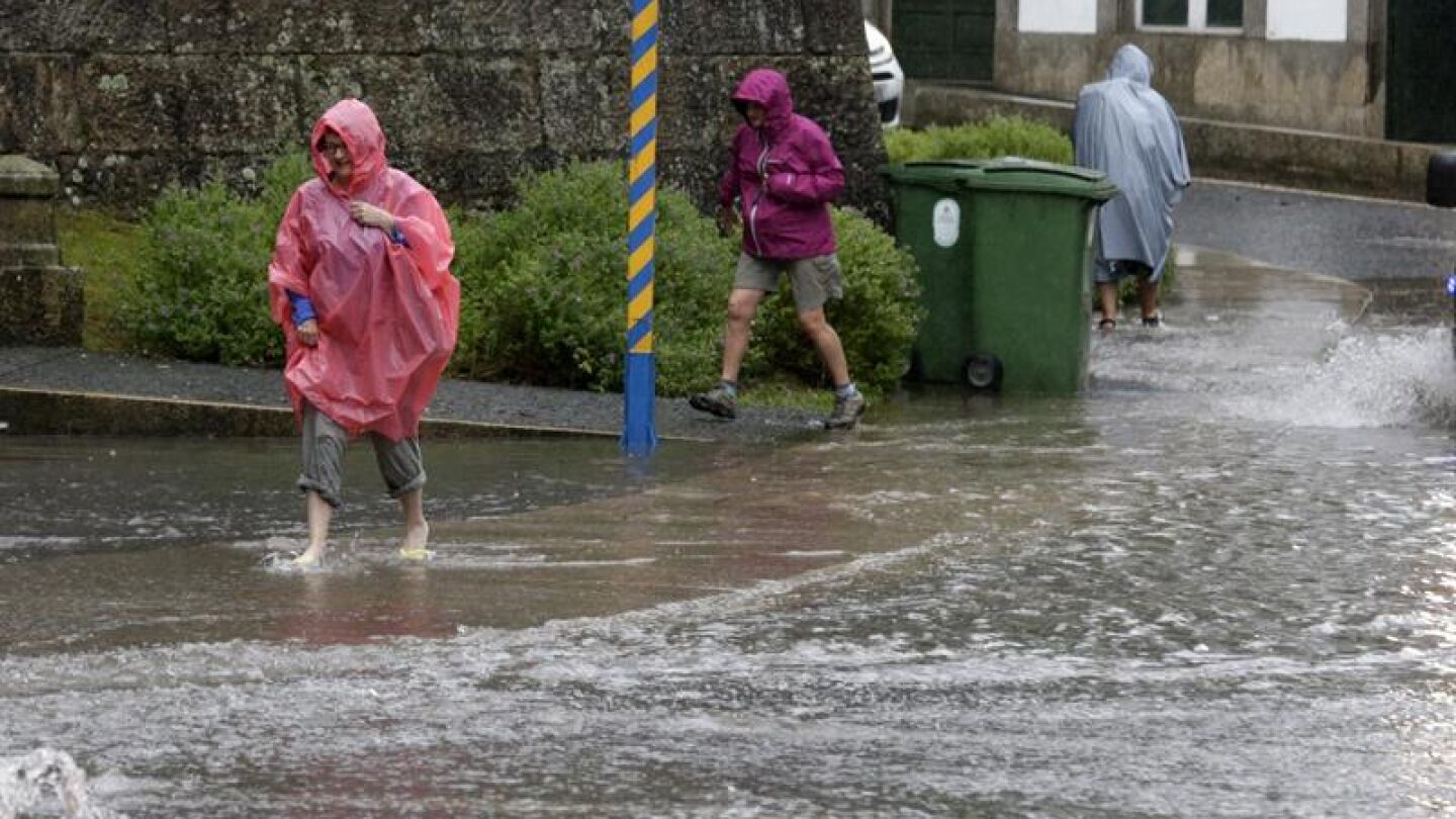 Varias personas intentan cruzar una calle anegada de agua