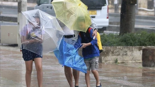 Varios viandantes luchan contra los fuertes vientos y la lluvia Varios viandantes luchan contra los fuertes vientos y la lluvia