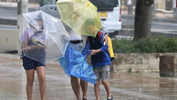 Varios viandantes luchan contra los fuertes vientos y la lluvia