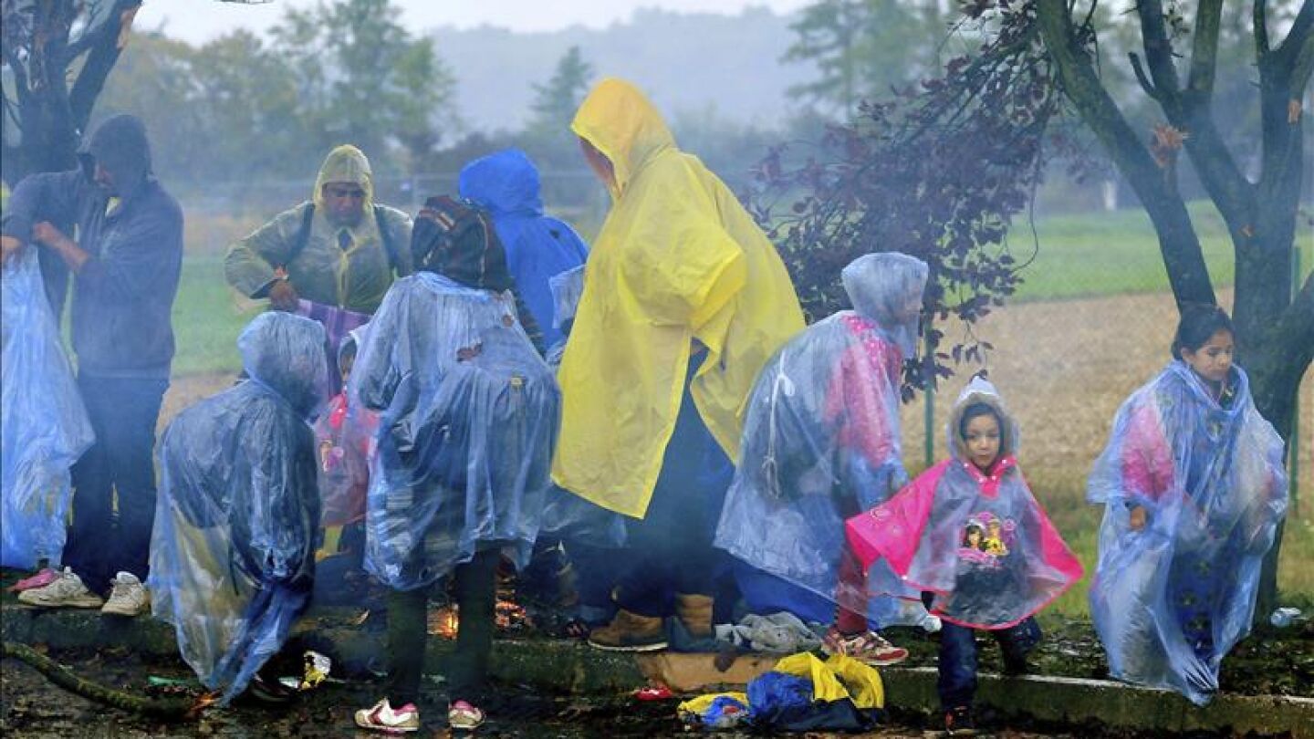 Refugiados esperan este lunes bajo la lluvia en la frontera entre Croacia y Eslovenia en Trnovec