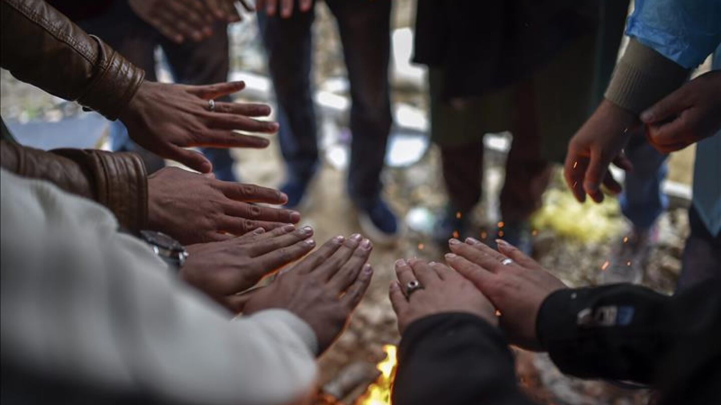 Un grupo de refugiados entra en calor junto a una hoguera