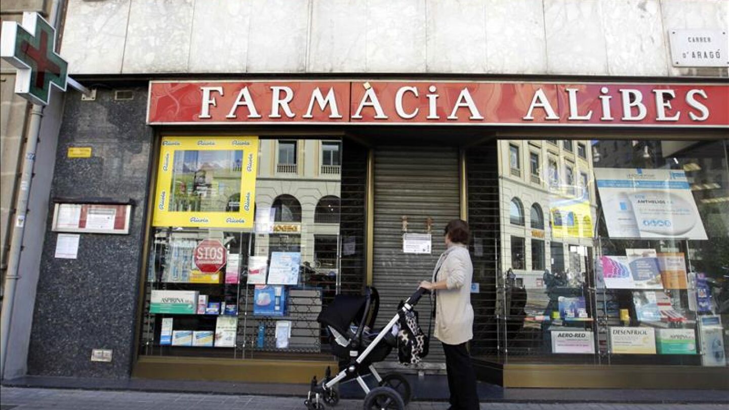 Una mujer contempla la fachada de una farmacia cerrada en el centro de Barcelona.