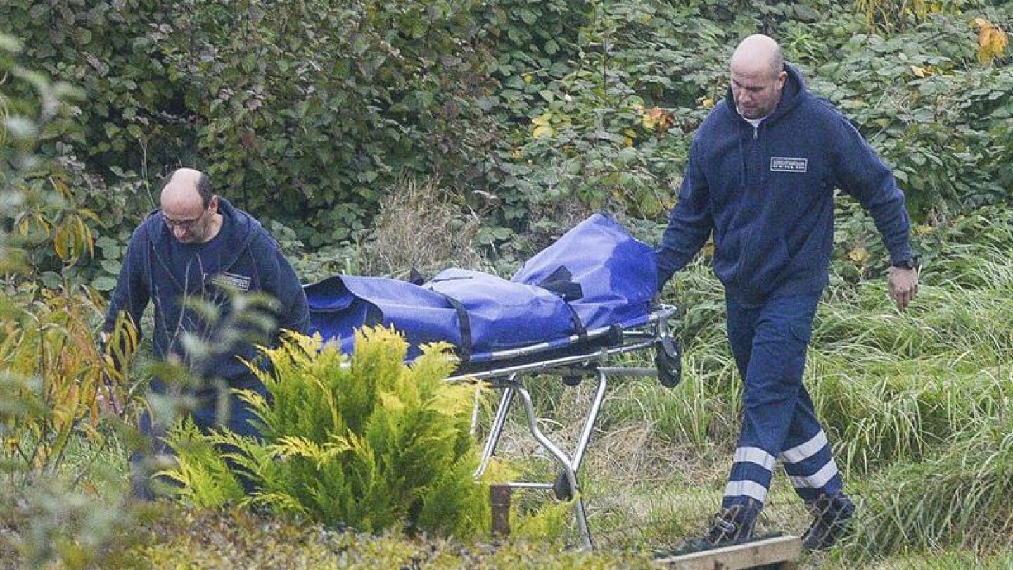 Dos m&eacute;dicos forenses trasladan el cuerpo de un ni&ntilde;o encontrado en una parcela en Luckenwalde, Alemania