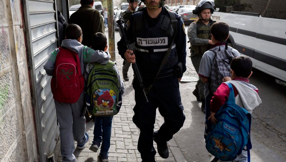 Niños caminan junto a agentes de la policía israelí.