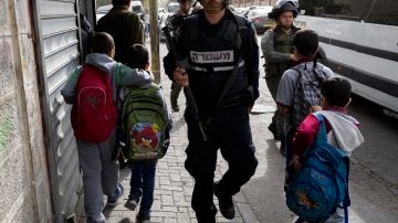 Niños caminan junto a agentes de la policía israelí.