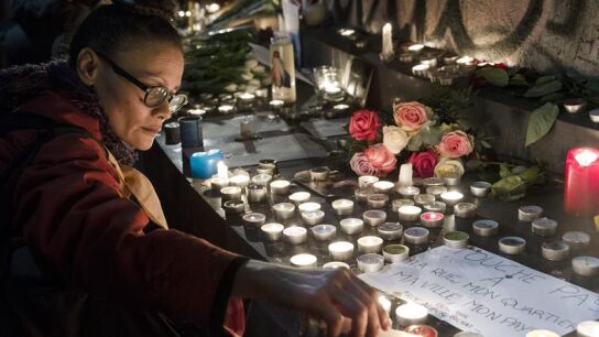  Una mujer enciende velas en la plaza de la Rep&uacute;blica en Par&iacute;s