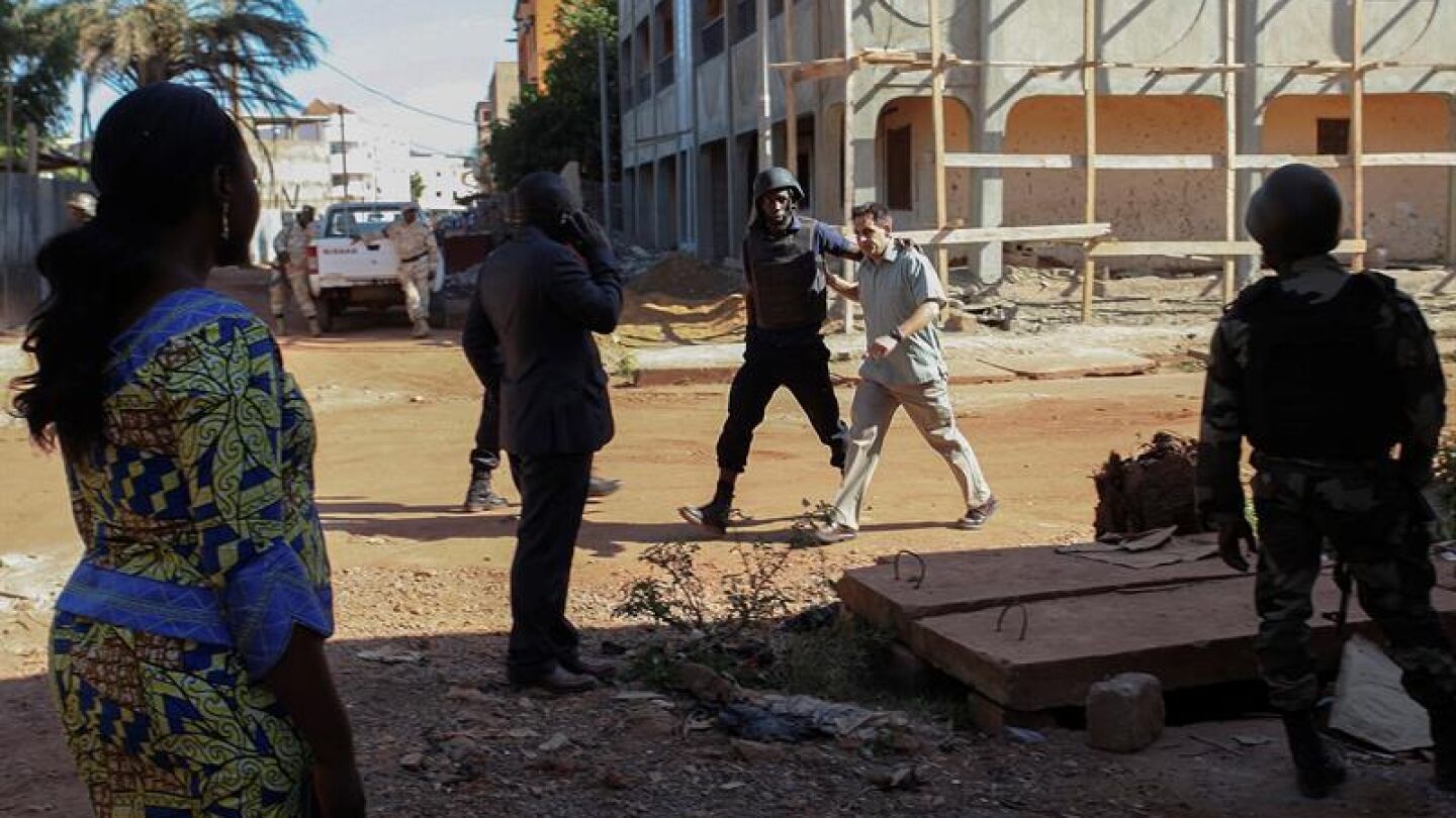 Un reh&eacute;n es escoltado por personal militar de Mali a su salida del hotel Radisson 