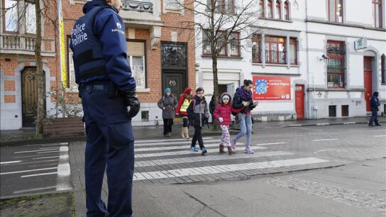 Un polic&iacute;a belga hace guardia a las puertas de un colegio en Bruselas