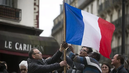Varias personas sujetan una bandera de Francia Varias personas sujetan una bandera de Francia