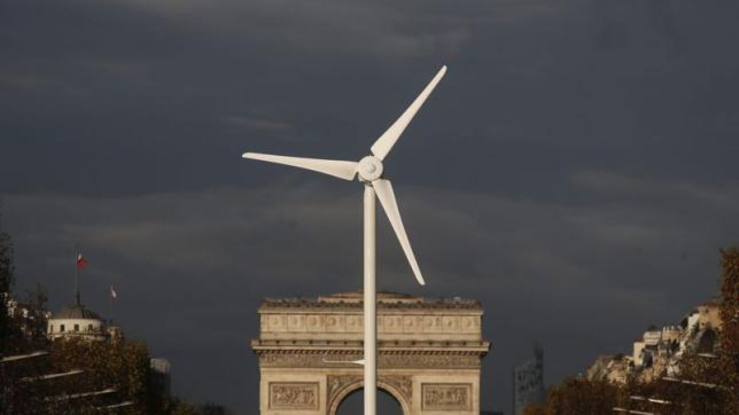 Un molino de energ&iacute;a e&oacute;lica delante del Arco de Triunfo