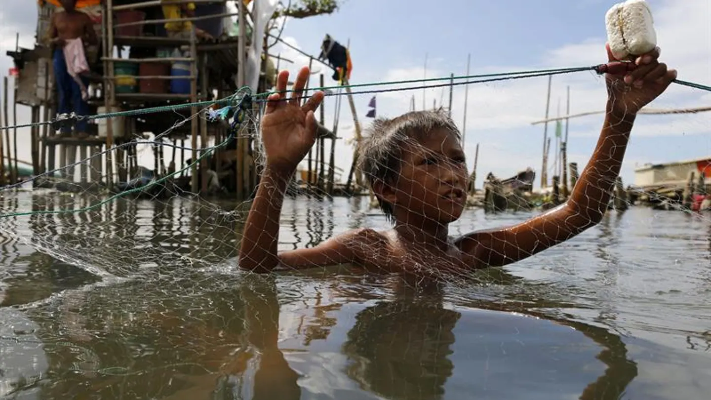 Un niño pesca tras el temporal en Filipinas Un niño pesca tras el temporal en Filipinas