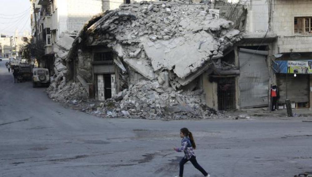 Una chica pasa por los edificios dañados de una zona controlada por los rebeldes de Maarat an-Numan