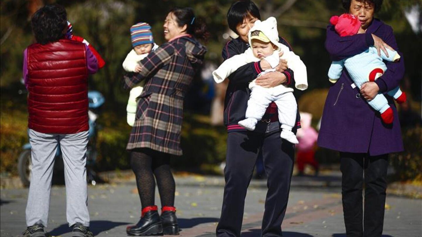 Varias mujeres sujetan en brazos a beb&eacute;s en un parque de Pek&iacute;n, China