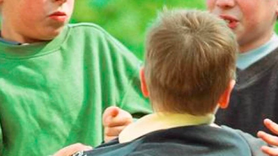 Representación de una escena de acoso escolar unos niños agreden a otro en el patio del colegio