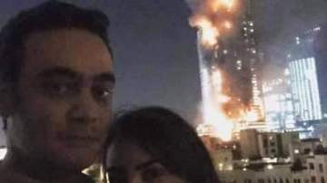 Una pareja se hace un selfie con un edificio en llamas