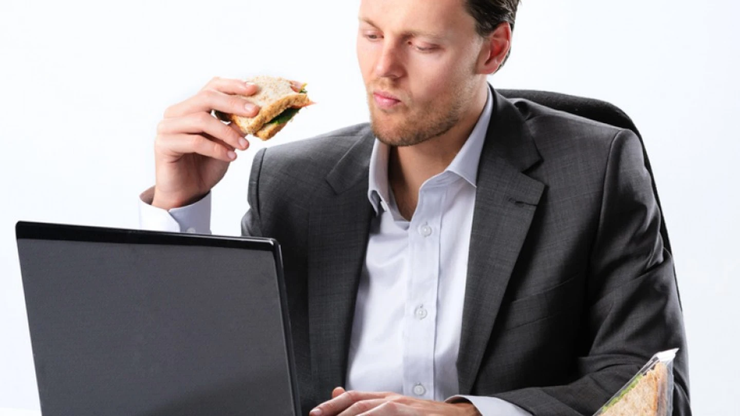 Un hombre comiendo un bocadillo en el trabajo Un hombre comiendo un bocadillo en el trabajo