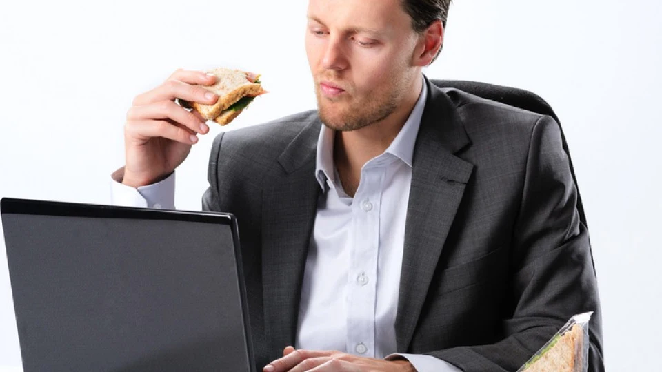 Un hombre comiendo un bocadillo en el trabajo Un hombre comiendo un bocadillo en el trabajo