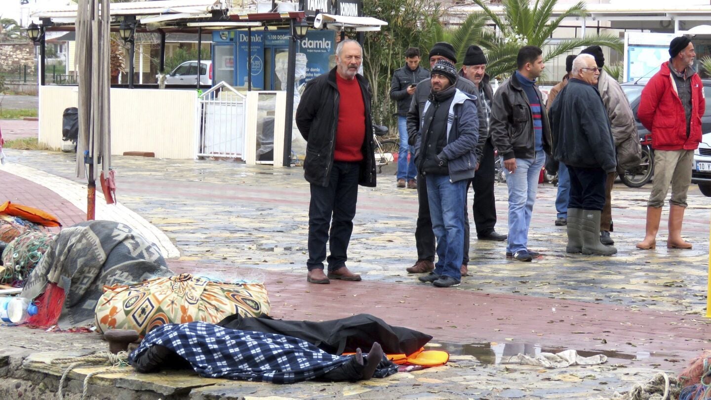 Varios curiosos permanecen cerca de varias v&iacute;ctimas ahogadas tras naufragar la embarcaci&oacute;n