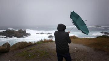 Un hombre ve cómo el viento le dobla el paraguas en A Coruña