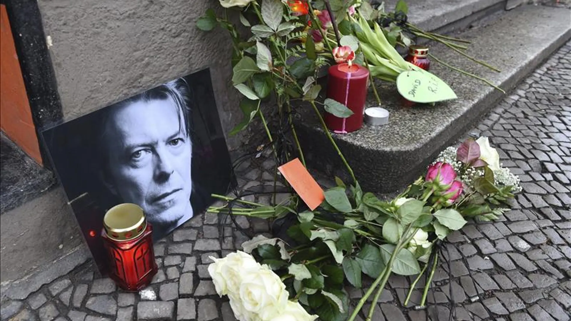 Flores y velas junto a una foto el cantante británico David Bowie