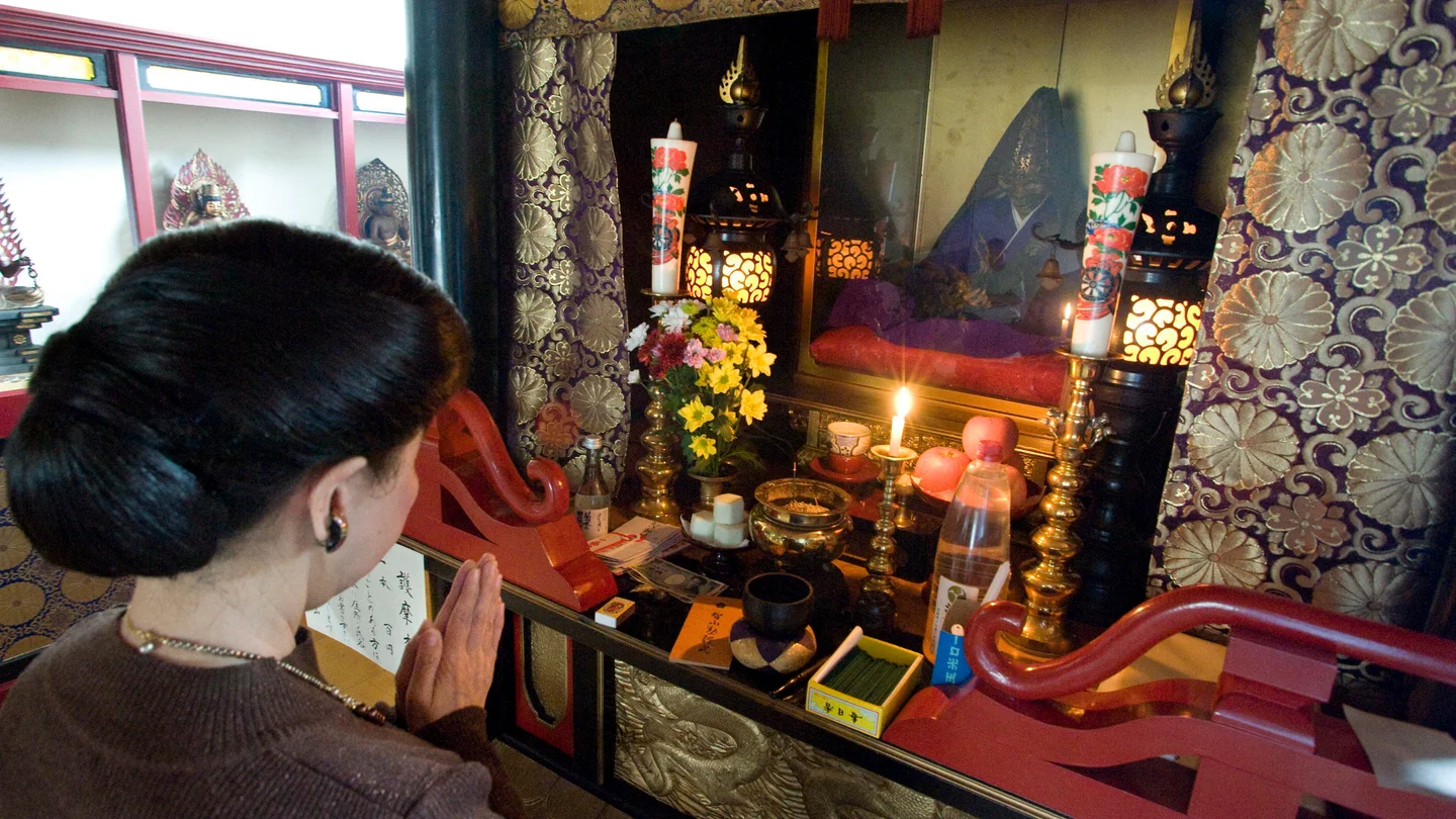 Imagen que muestra a una mujer que reza delante de un buda viviente Imagen que muestra a una mujer que reza delante de un buda viviente