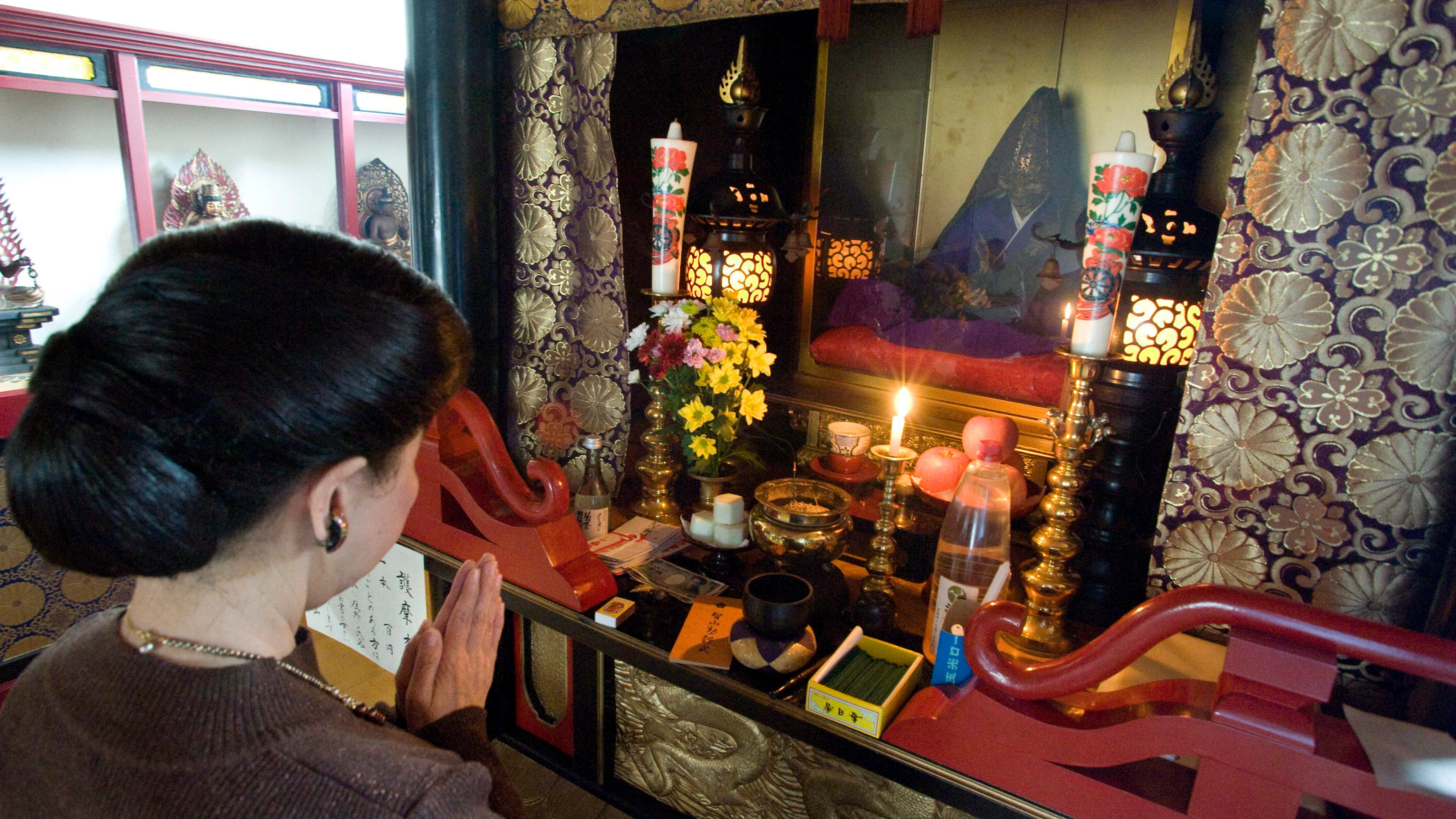 Imagen que muestra a una mujer que reza delante de un buda viviente