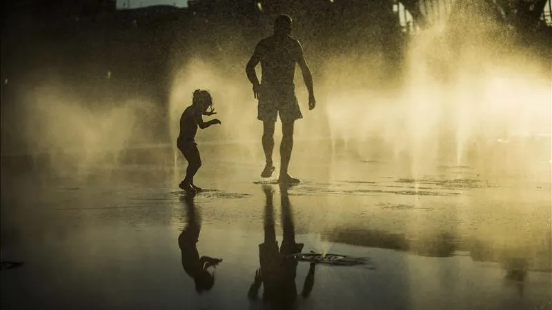 Un padre y su hijo jugando en una fuente