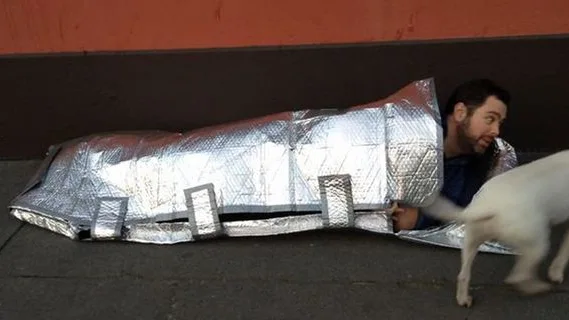 Un joven prueba un saco de dormir resistente al agua y al fuego Un joven prueba un saco de dormir resistente al agua y al fuego