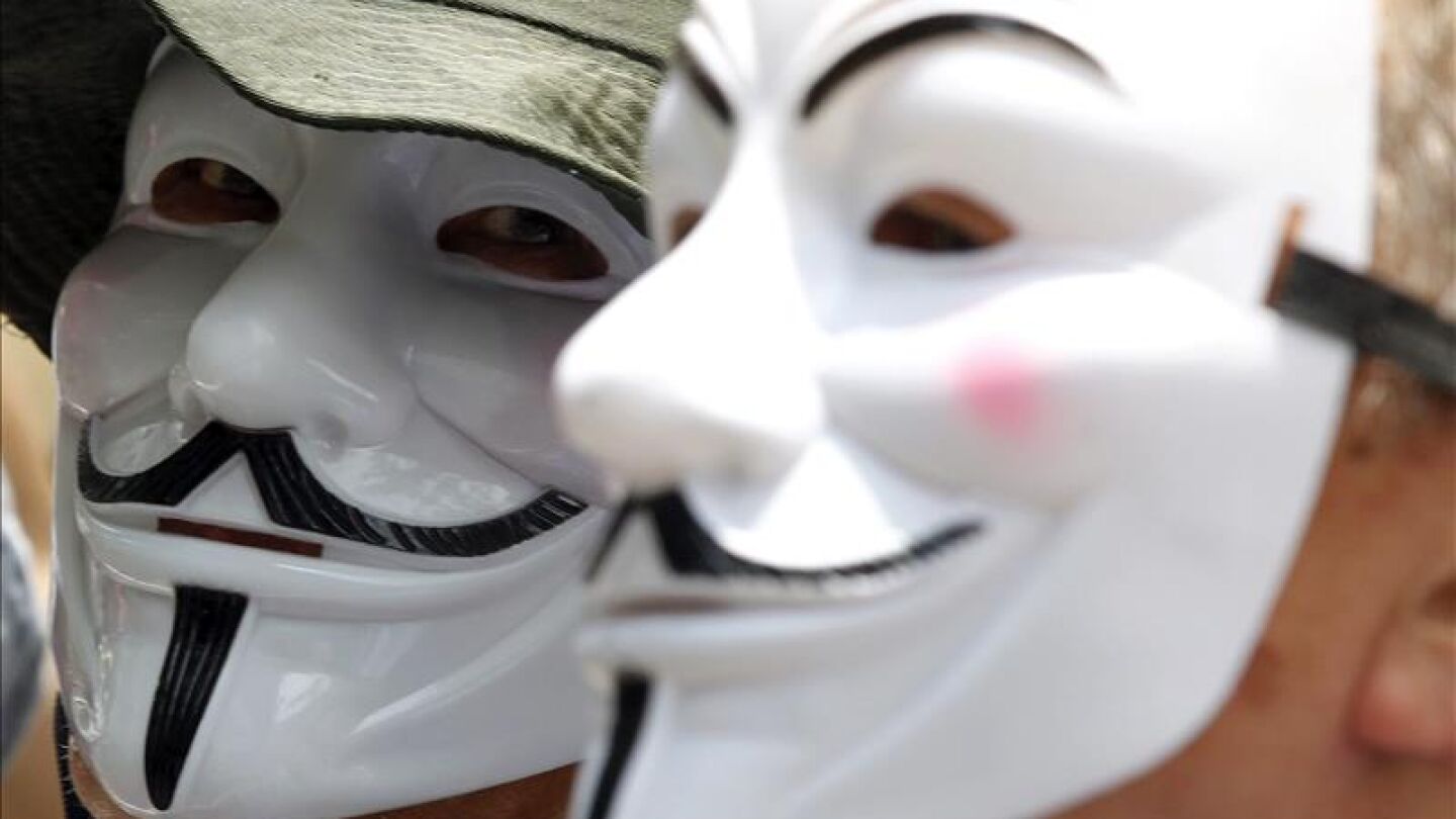 Dos personas con las caretas caracter&iacute;sticas de Anonymous
