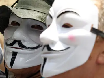 Dos personas con las caretas características de Anonymous Dos personas con las caretas características de Anonymous
