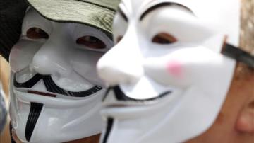 Dos personas con las caretas características de Anonymous