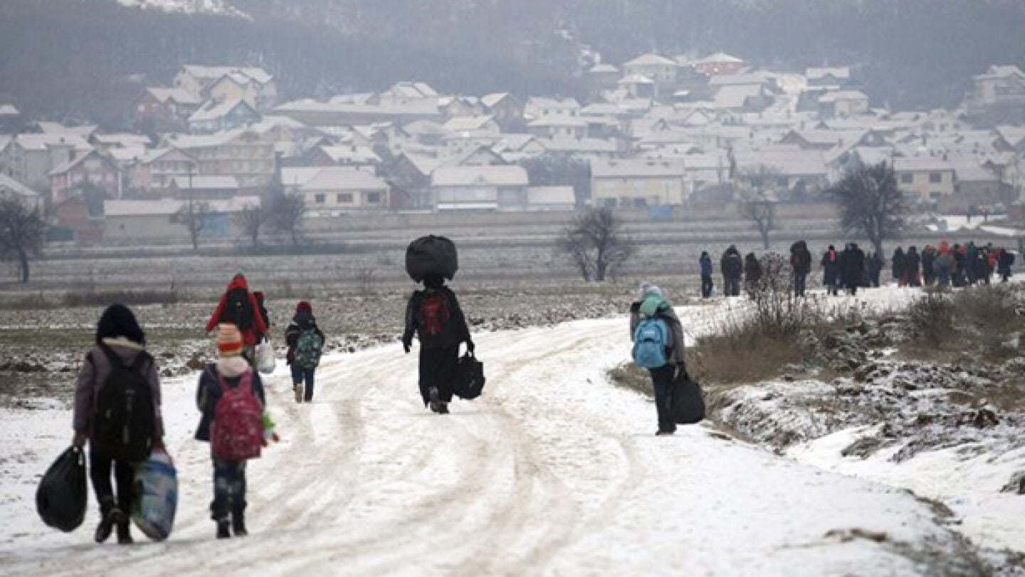 Un grupo de refugiados avanzando por un camino nevado