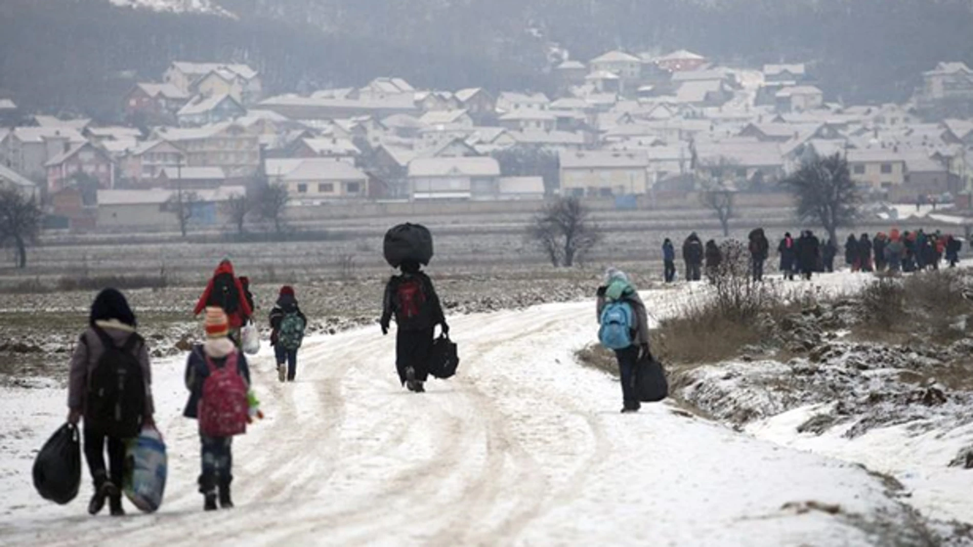 Un grupo de refugiados avanzando por un camino nevado