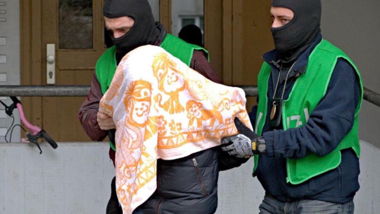 Agentes de polic&iacute;a escoltan a uno de los detenido