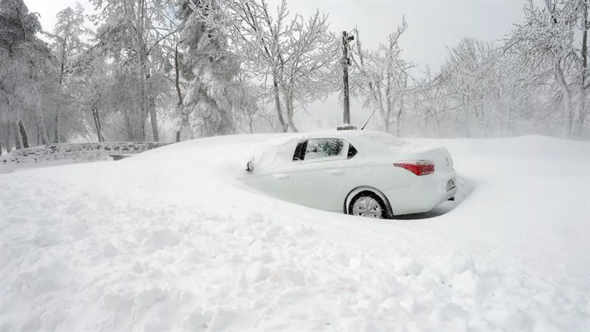 En la foto un coche parcialmente sepultado por la nieve en O Cebreiro.