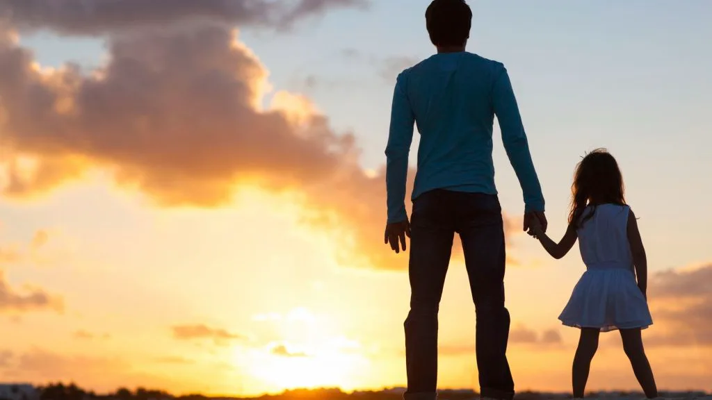 Un padre con su hija durante la puesta de sol