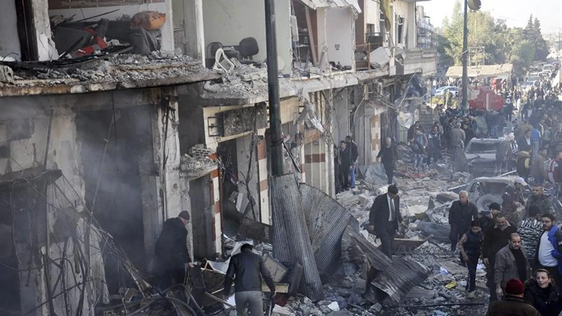 Policías sirios inspeccionan el lugar donde se ha producido un atentado en Homs, Siria