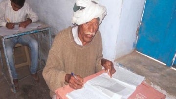 Charan Yadav con 77 años sentado en su pupitre de clase