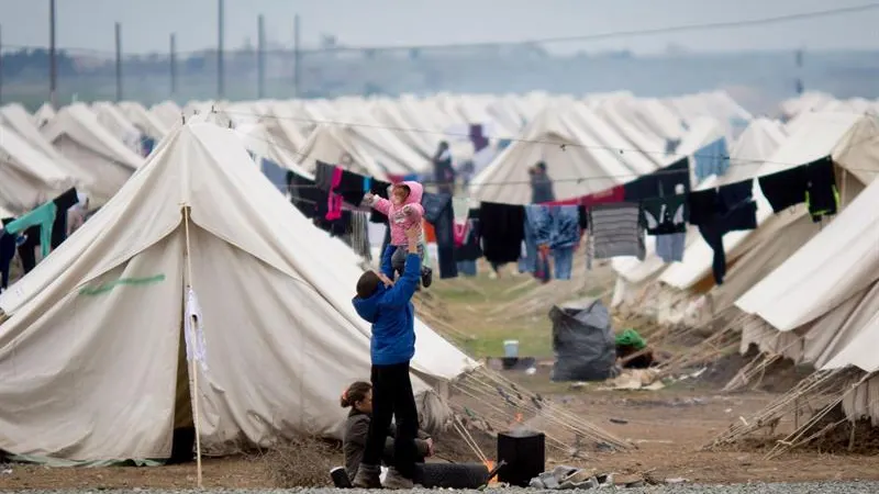 Un hombre juega con su hijo en el campo de refugiados de Idomeni