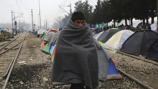 Un joven refugiado cubre su cuerpo con un manta en el campamento provisional de Idomeni, en la frontera entre Grecia y Macedonia (Grecia). Un joven refugiado cubre su cuerpo con un manta en el campamento provisional de Idomeni, en la frontera entre Grecia y Macedonia (Grecia).