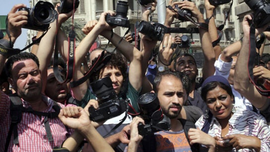 Periodistas alzan sus c&aacute;maras en se&ntilde;al de protesta durante una manifestaci&oacute;n en El Cairo