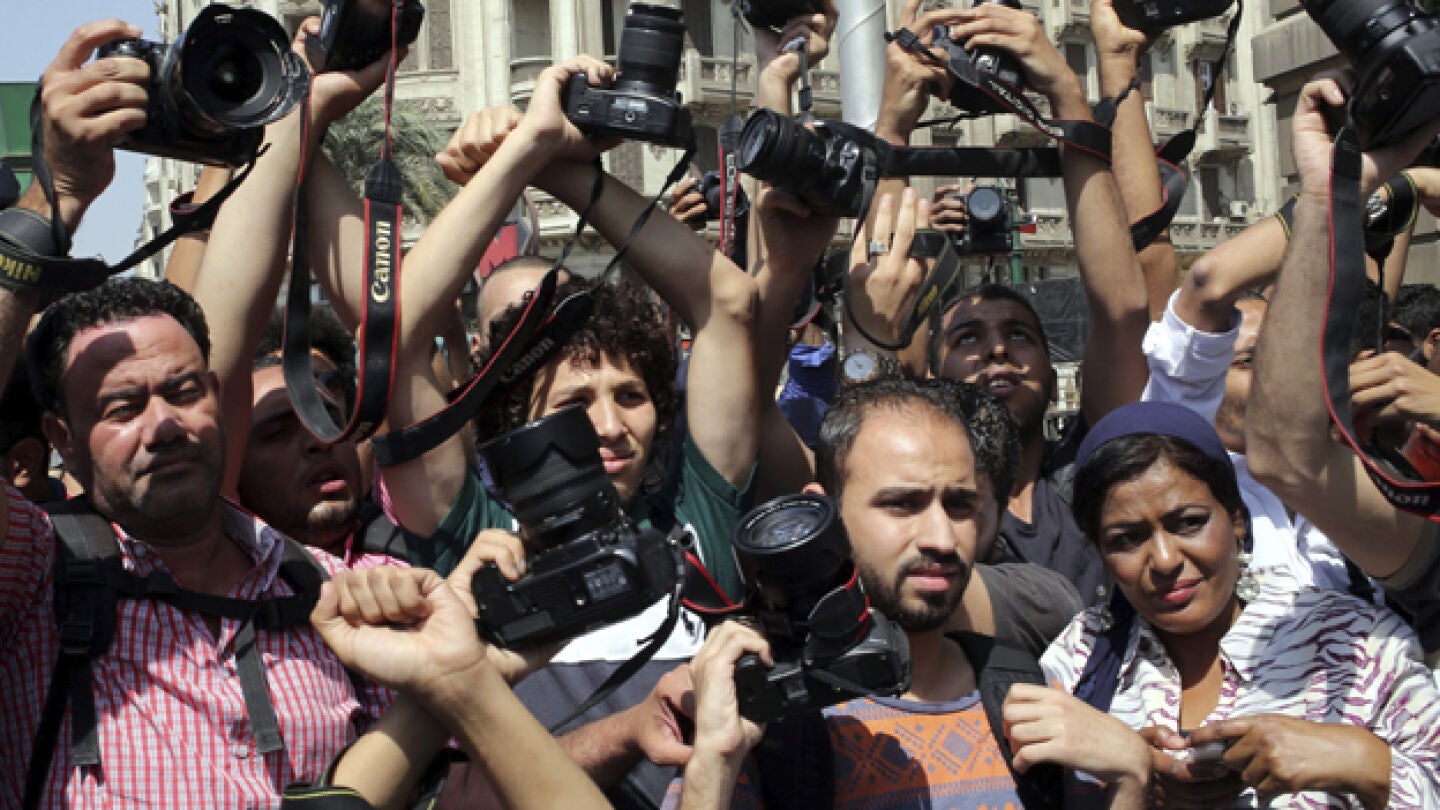 Periodistas alzan sus c&aacute;maras en se&ntilde;al de protesta durante una manifestaci&oacute;n en El Cairo