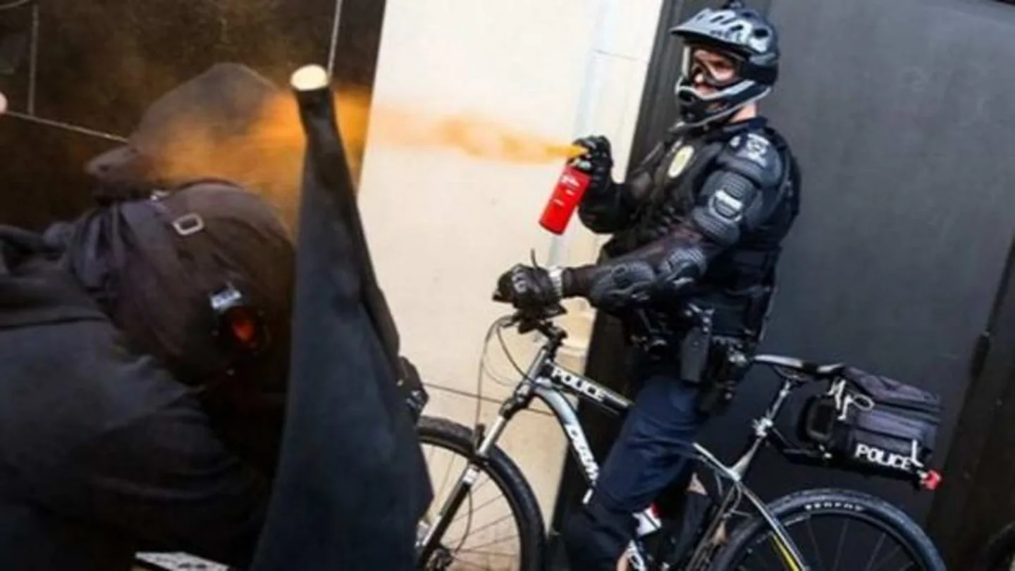 Un policía esparce gas pimienta sobre los manifestantes Un policía esparce gas pimienta sobre los manifestantes